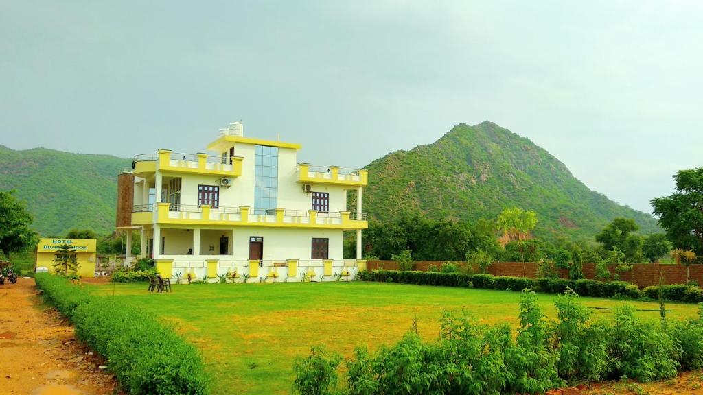 a house in a field with mountains in the background at Hotel Divine Palace Pushkar in Pushkar