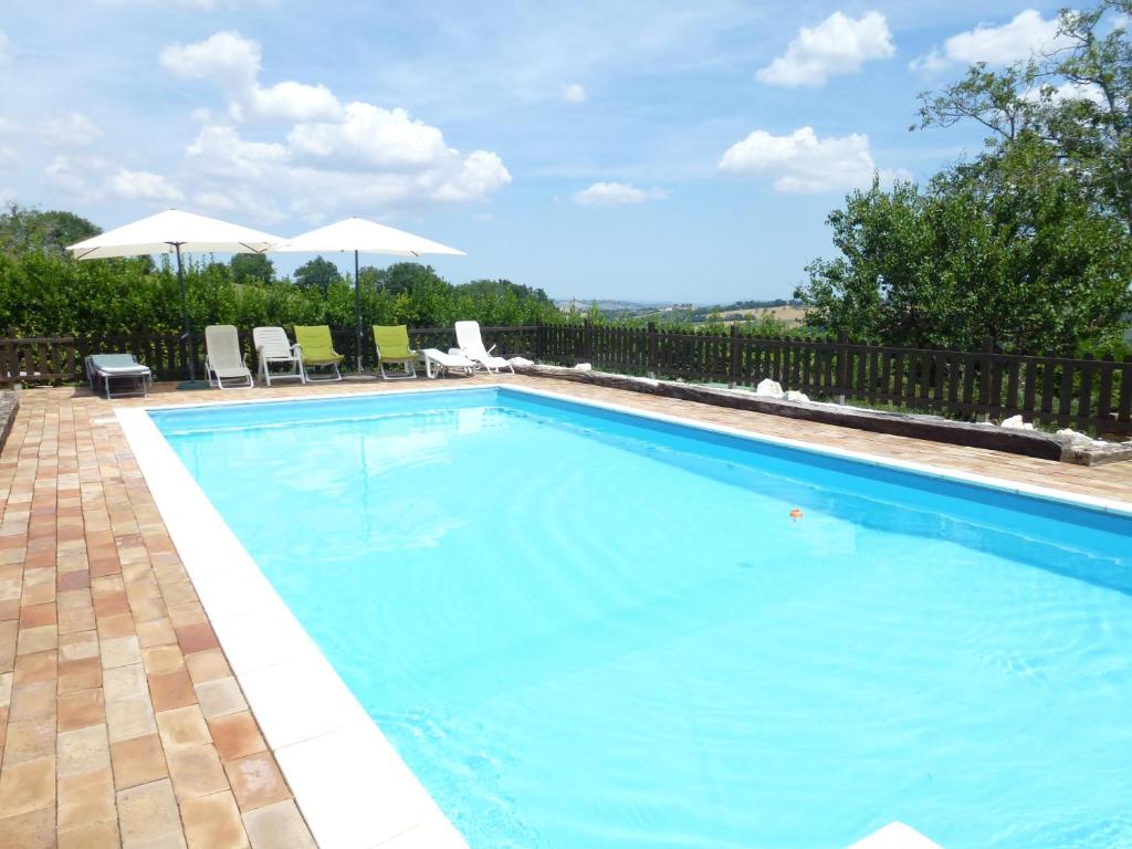 a large blue swimming pool with chairs and umbrellas at Il Casale di Aurora Country House in Colmurano
