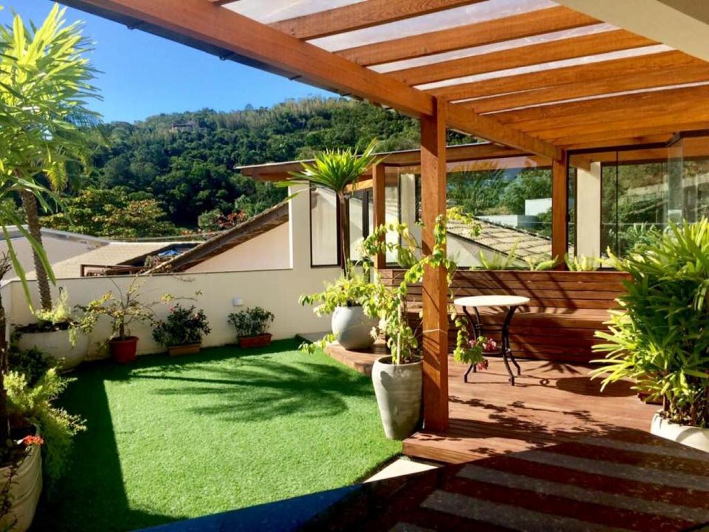 um pátio com relva verde e uma pérgula de madeira em Pousada Pedra Rosa em Florianópolis