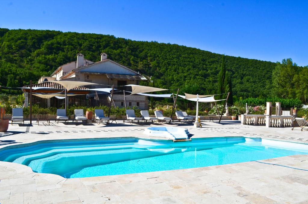 uma piscina com cadeiras e guarda-sóis e um edifício em Bastide De Mazan em Riez