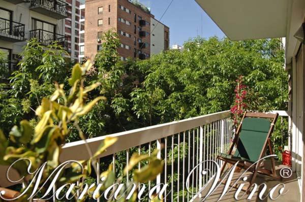 a balcony with a chair and some trees and buildings at Mariu Apartment in Buenos Aires