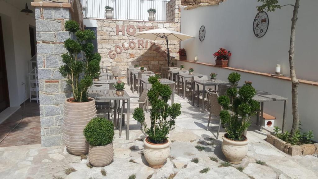 a restaurant with potted plants and tables and chairs at Hotel Goloritzé in Baunei