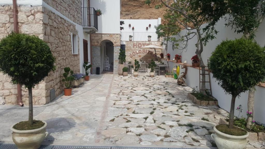 an alley with potted trees and a building at Hotel Goloritzé in Baunei