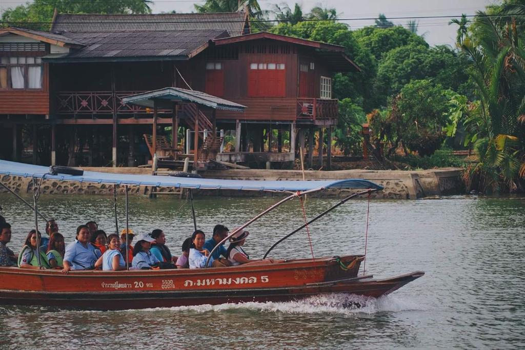 Bansuwan Homestay في أمفاوا: مجموعة من الناس تركب قارب في الماء