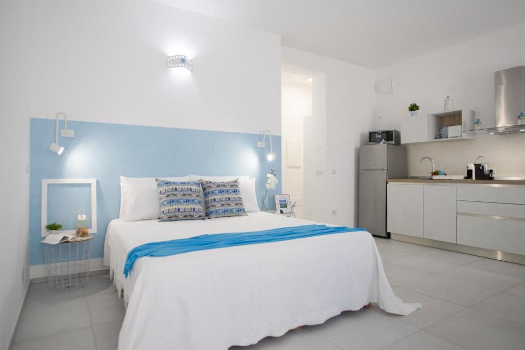 a white bedroom with a large bed and a kitchen at Il Pescatore di Sogni in Porto Torres
