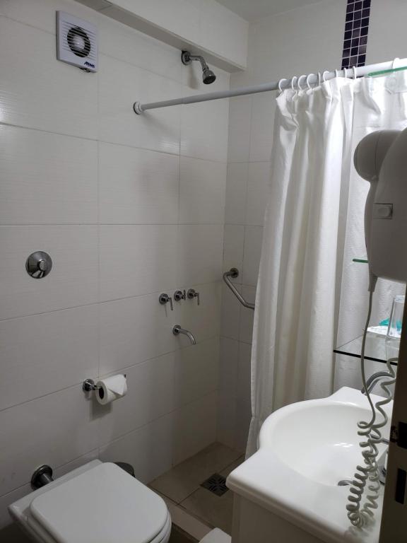 a white bathroom with a shower and a toilet at Hotel Continental in Posadas