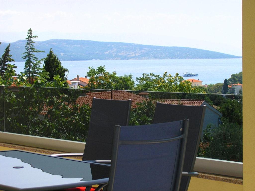 a balcony with two chairs and a view of the water at Apartmani Krajinovic in Krk