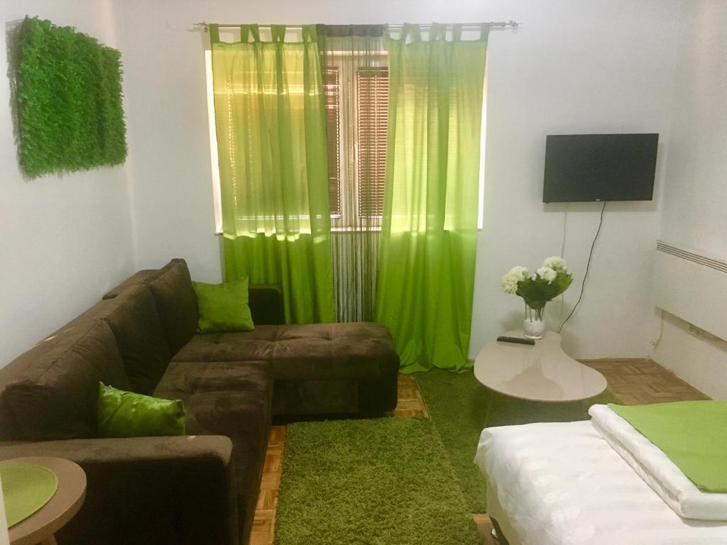 - un salon avec un canapé et un rideau vert dans l'établissement Apartment Green, à Sarajevo