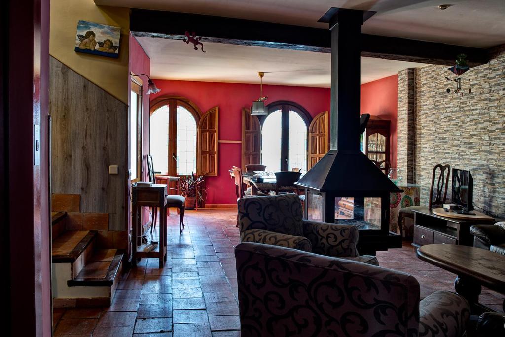 sala de estar con paredes rojas y chimenea en El Jardín de la Alegría, en Zamarramala