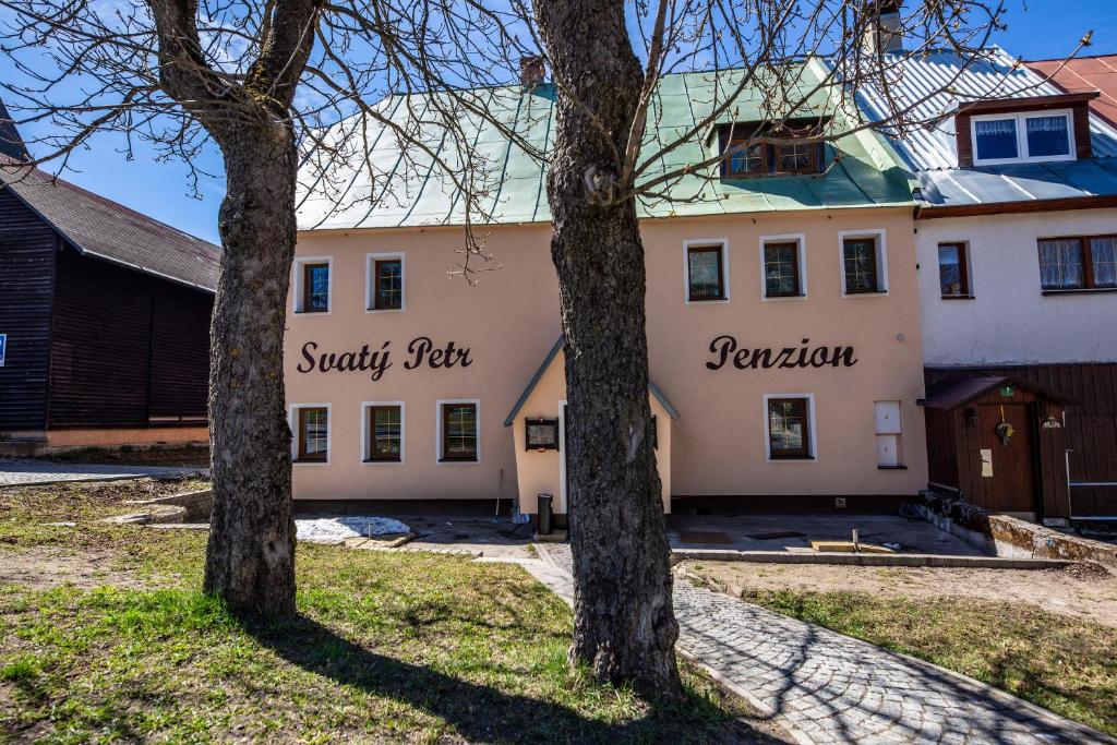 two trees in front of a white building at Penzion Svatý Petr in Boží Dar