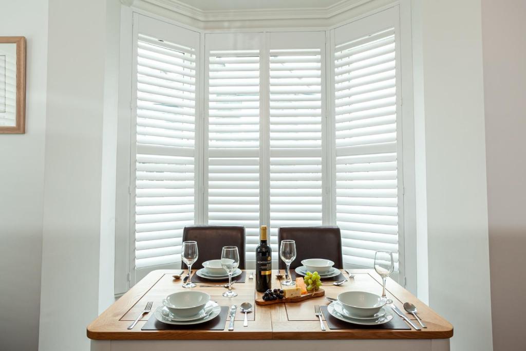 a dining room table with glasses and a bottle of wine at Carlton 2 a large modern Keswick appt with parking in Keswick