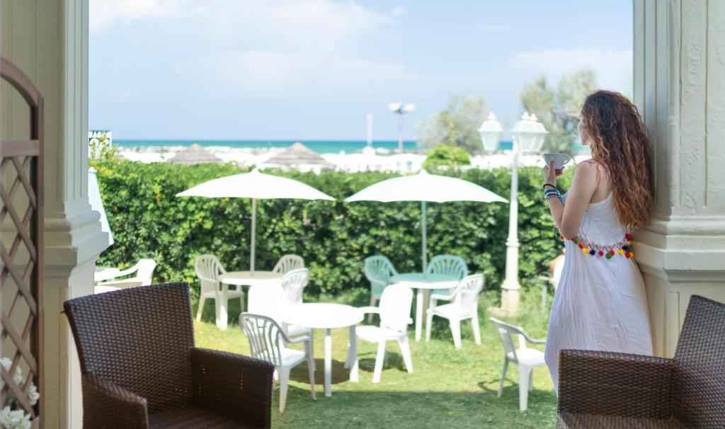 a woman taking a picture of a patio with tables and chairs at Hotel Orizzonte in Bellaria-Igea Marina