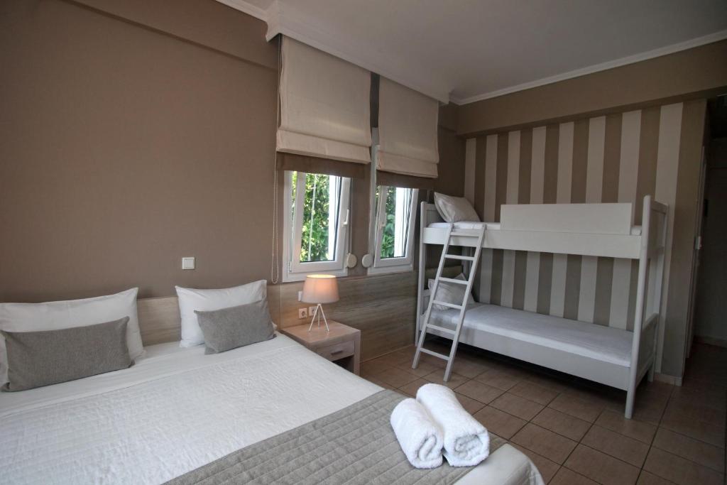 a bedroom with two beds and a bunk bed and a ladder at Nostos Hotel in Afitos