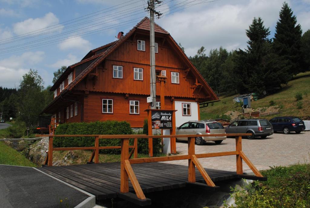a wooden house with a wooden bridge in front of it at Roubenka-Mila in Ostružná