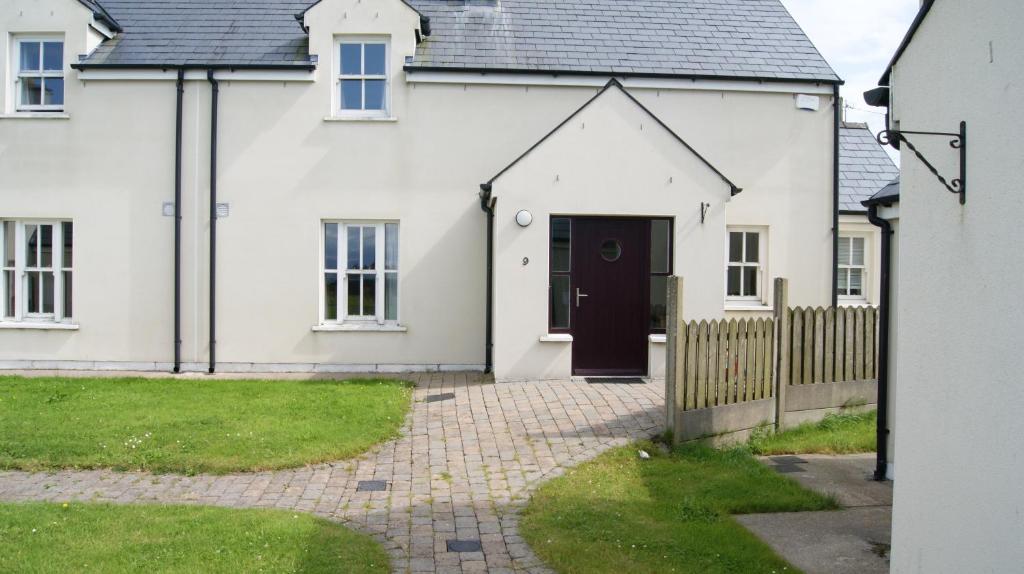 a white house with a black door at No 9 Seanachaí Holiday Homes Holiday home in Dungarvan