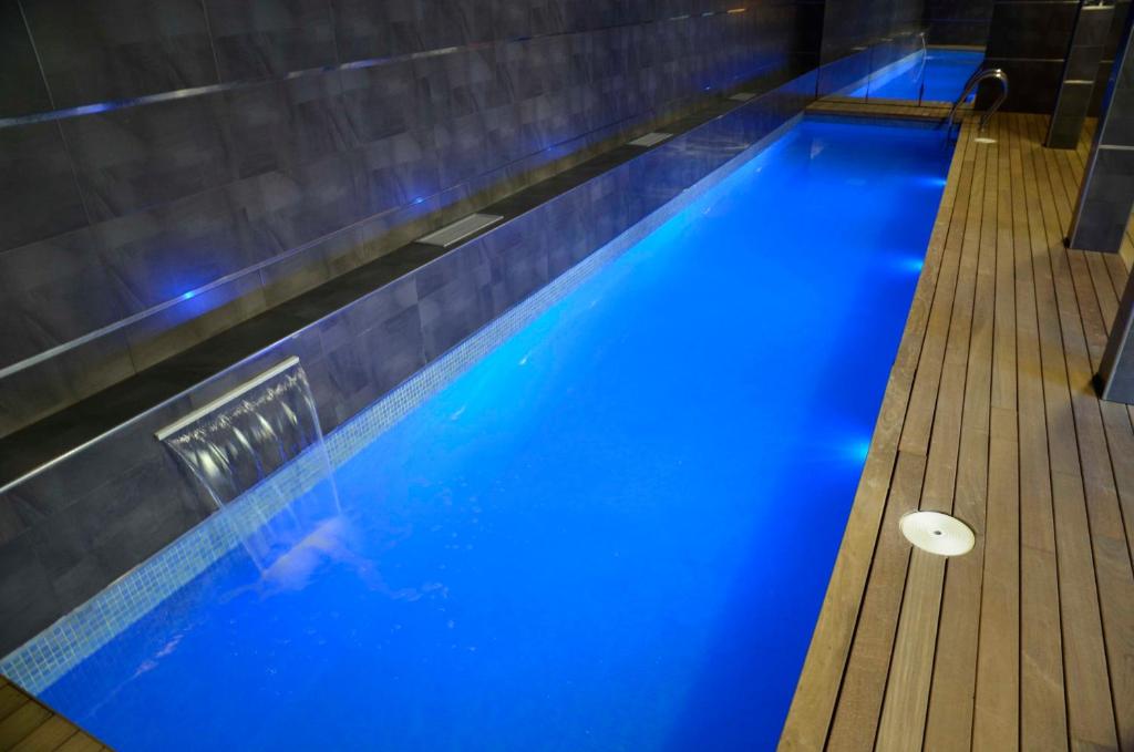 een zwembad met blauw water in een fitnessruimte bij Apartamentos Spa Cantabria Infinita in Cillorigo de Liebana