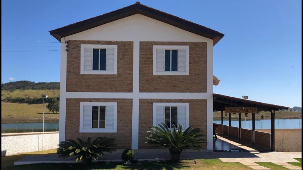Casa de Campo às margens do lago de furnas في بوا إسبيرانسا: منزل بني وبيضاء مع سياج