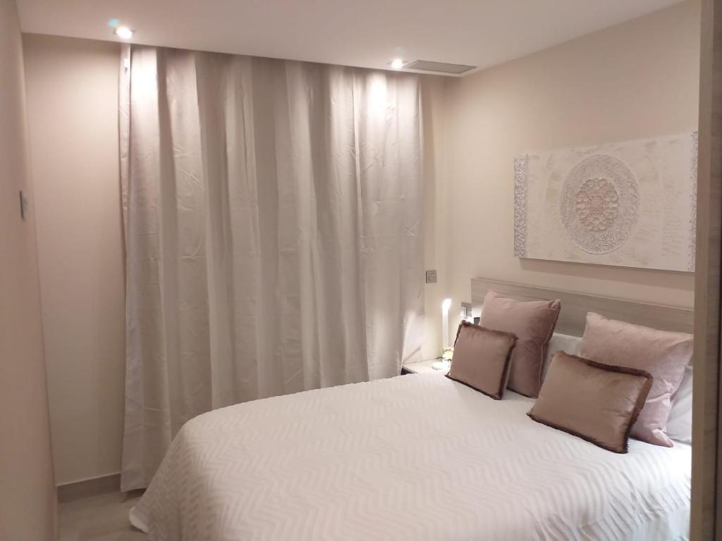 una camera da letto con un grande letto bianco con due cuscini di Apartamentos Vacacionales Joctis, 2º B a Fuengirola