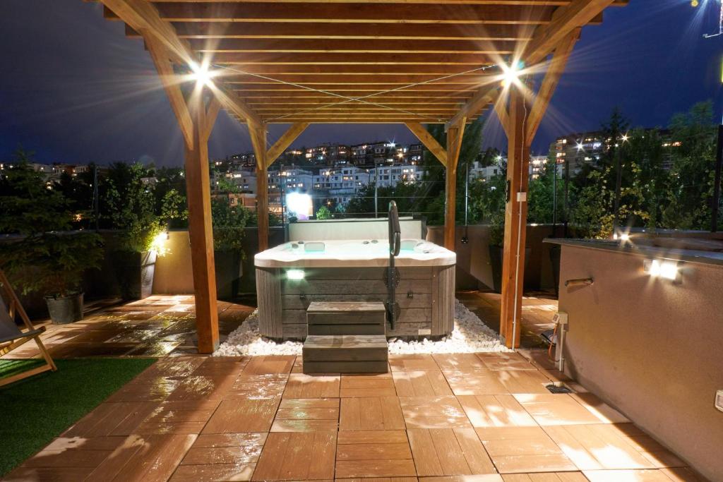 - un kiosque avec une baignoire sur la terrasse la nuit dans l'établissement OLYMPIC 84 Apartments, à Sarajevo