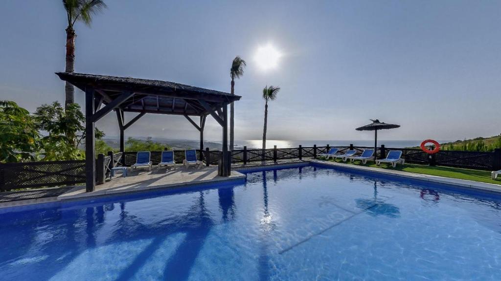 Una gran piscina azul con un cenador en Apartamentos Manilva Green, en Manilva