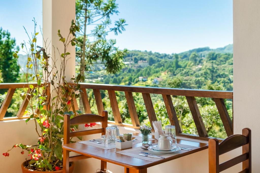a table on a balcony with a view at Pousada Jardim da Mantiqueira in Monte Verde