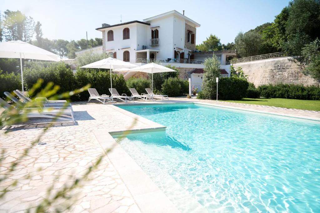 a swimming pool with chairs and a house in the background at Tenuta Cardinale in Manduria