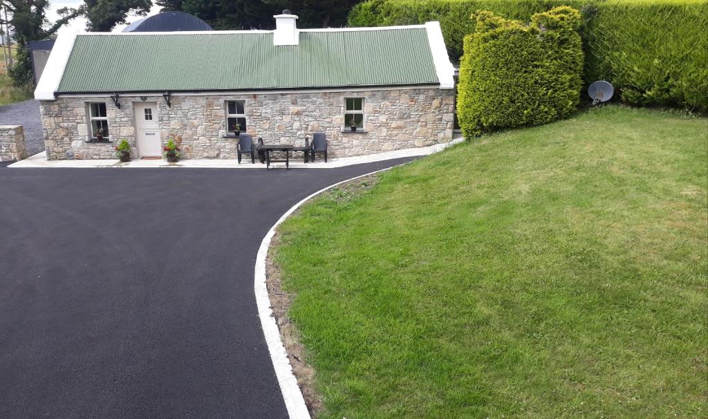 a driveway leading to a stone house with a table at Swallows Cottage in Swinford