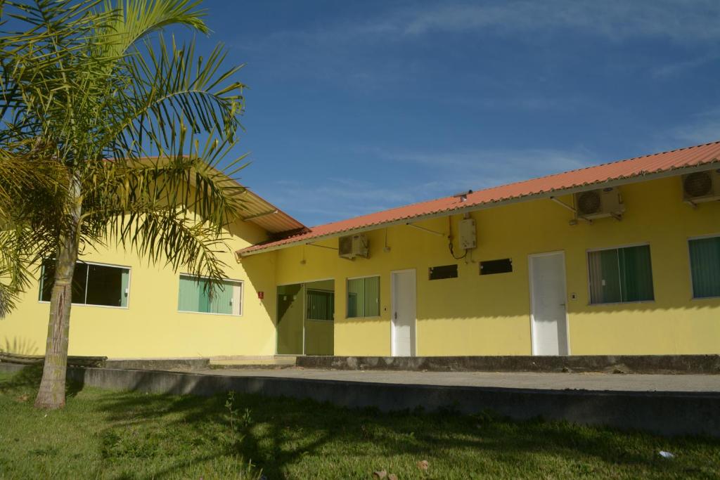 a yellow building with a palm tree in front of it at Pousada Santo Antônio in Piraí
