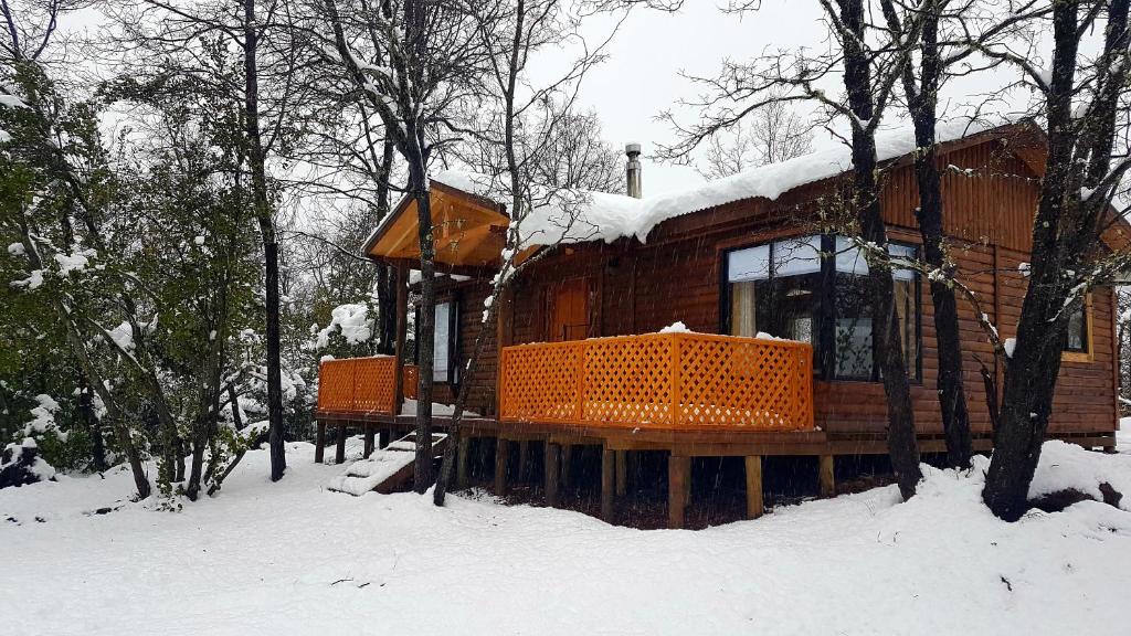 una cabaña de madera en la nieve con nieve en Montblanc, en Las Trancas