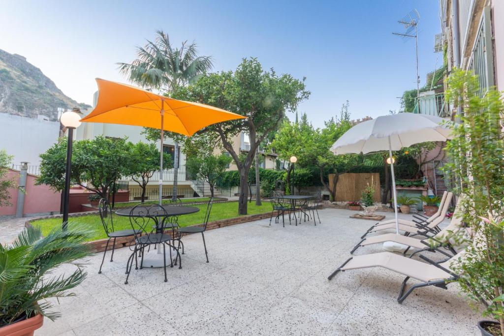 un patio con tavoli, sedie e ombrelloni di Villa Valverde Apartments e B&B a Taormina
