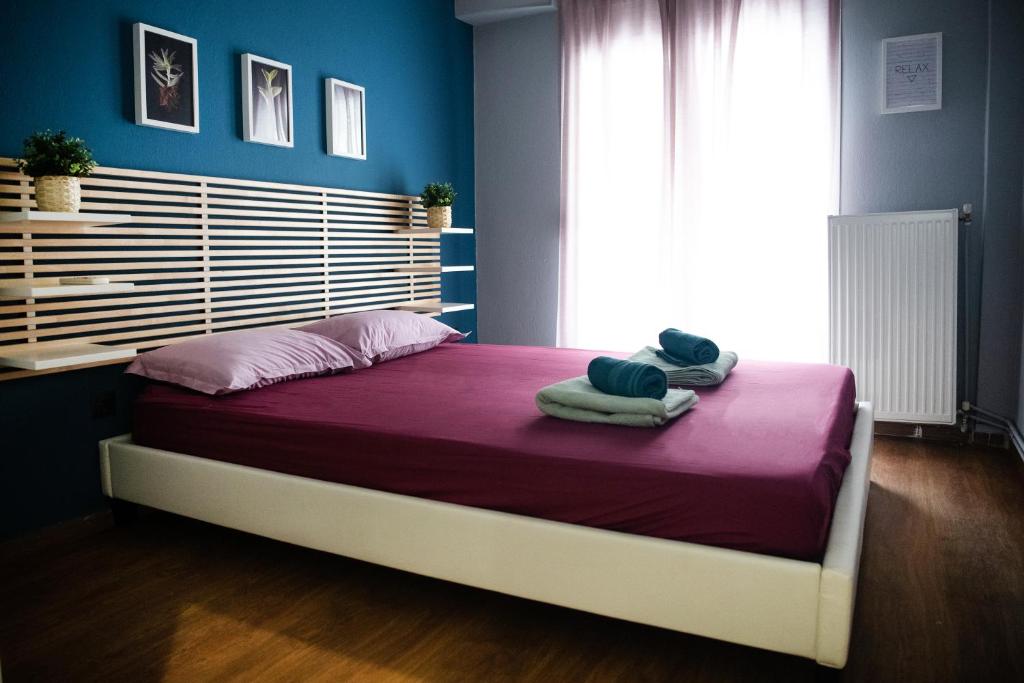 um quarto com uma cama com lençóis roxos e uma janela em Grey & Cozy Luxury Apartment em Tessalônica