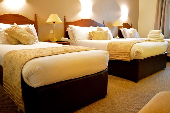 a hotel room with two beds and two lamps at Hotel Curracloe in Curracloe