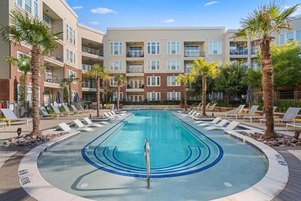 a swimming pool with lounge chairs and palm trees in a apartment complex at Kasa Frisco Dallas in Frisco
