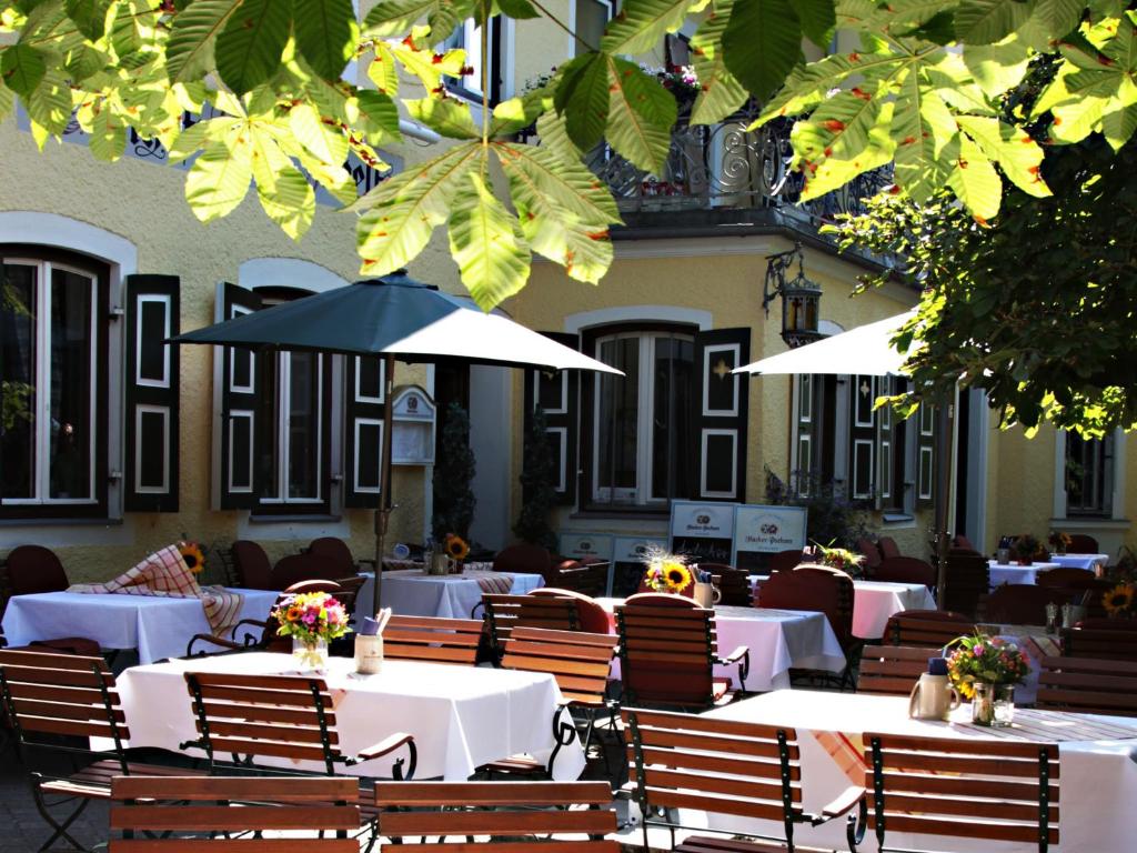 ein Restaurant mit Tischen, Stühlen und Sonnenschirmen in der Unterkunft Gasthaus Poelt in Feldafing