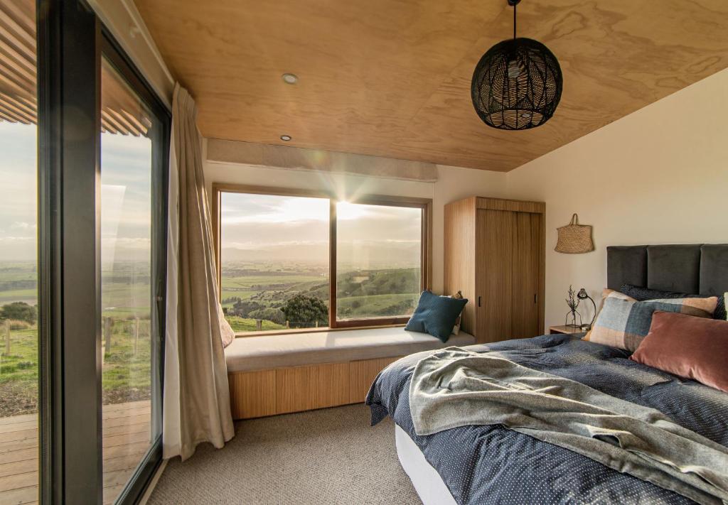 a bedroom with a bed and a large window at Whitimanuka Retreat in Martinborough 