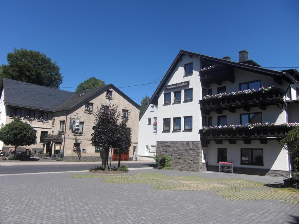 ein weißes Gebäude mit Blumen an der Seite einer Straße in der Unterkunft Hotel Restaurant Eifelstube in Weibern