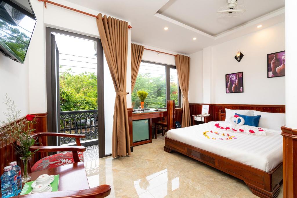 una camera con letto, scrivania e balcone di Family Hotel a Hoi An