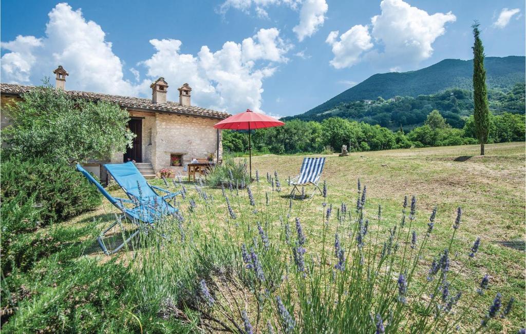 una casa con due sedie e un ombrellone in un campo di Casalino a Bazzano di Spoleto