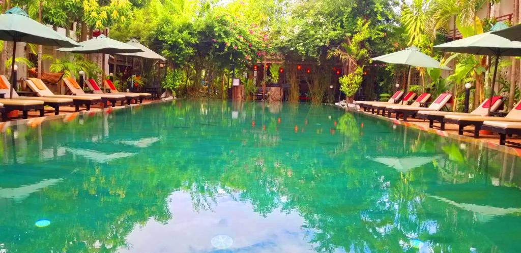 ein Swimmingpool mit Stühlen und Sonnenschirmen in der Unterkunft La Niche D'angkor Boutique Hotel in Siem Reap