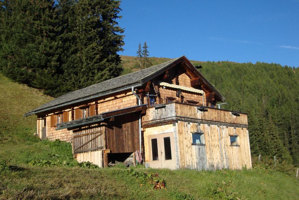 ein altes Holzgebäude auf einem Hügel auf einem Feld in der Unterkunft Turner-Hütte in Heiligenblut