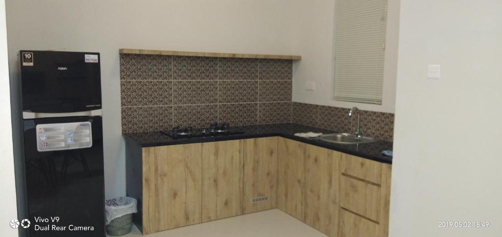 a kitchen with wooden cabinets and a black refrigerator at SleepRest @ The Home Shoutlink in Nagoya