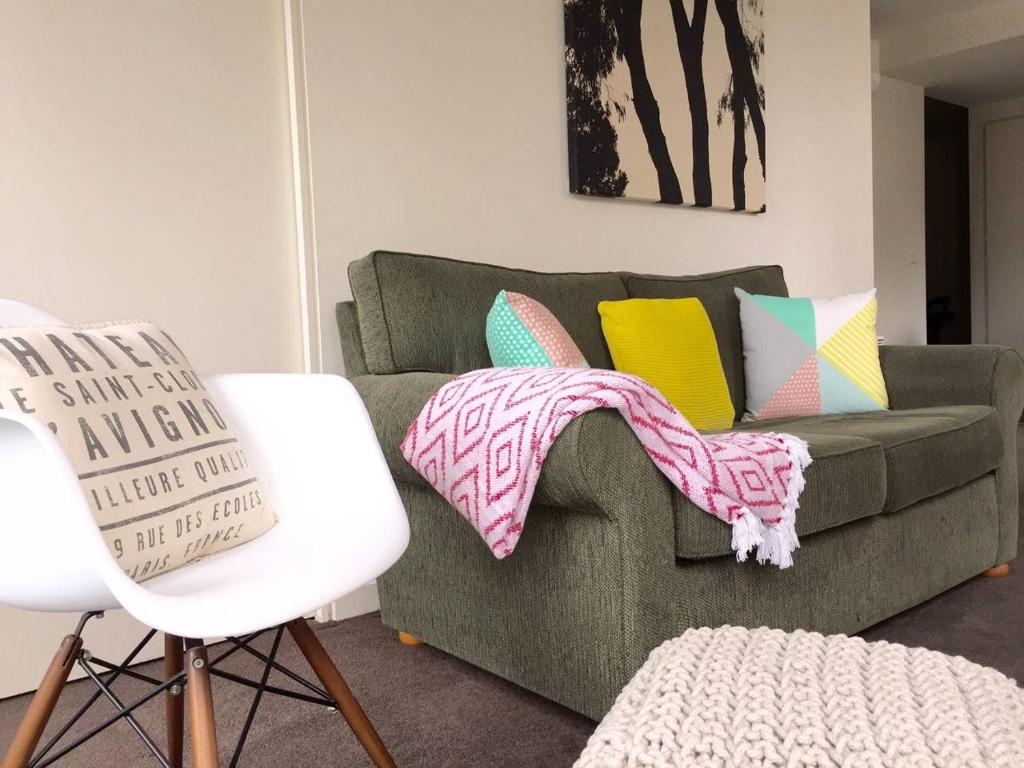 ein Wohnzimmer mit einer grünen Couch mit bunten Kissen in der Unterkunft Tribeca in Melbourne