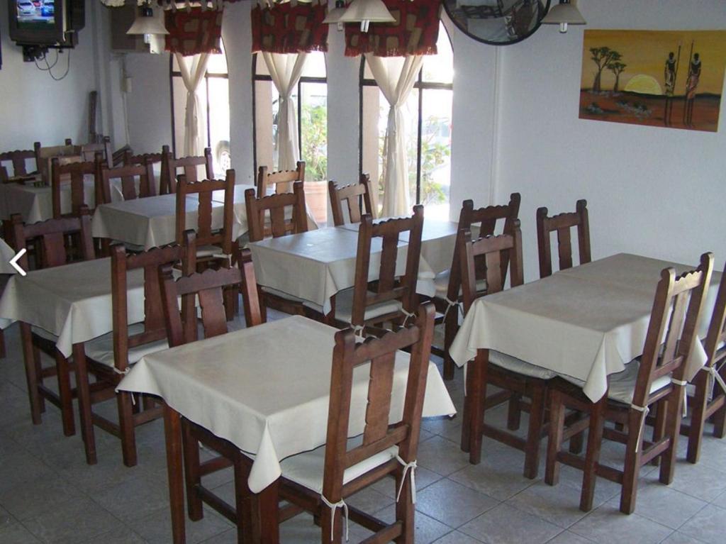 a dining room with tables and chairs and windows at Apart Hotel Monaco in Santa Teresita