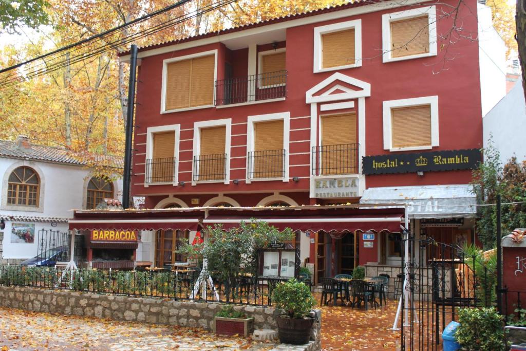 - un bâtiment rouge avec un restaurant en face dans l'établissement Hostal Rural Rambla, à Alcalá del Júcar