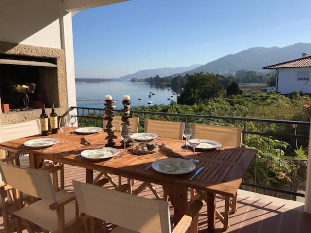 einen Holztisch auf einem Balkon mit Blick auf das Wasser in der Unterkunft Trajadinha - Swedish House in Caminha