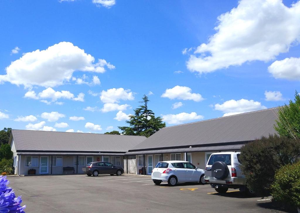 un edificio con dos coches estacionados en un estacionamiento en Braemar Motor Lodge, en Palmerston North