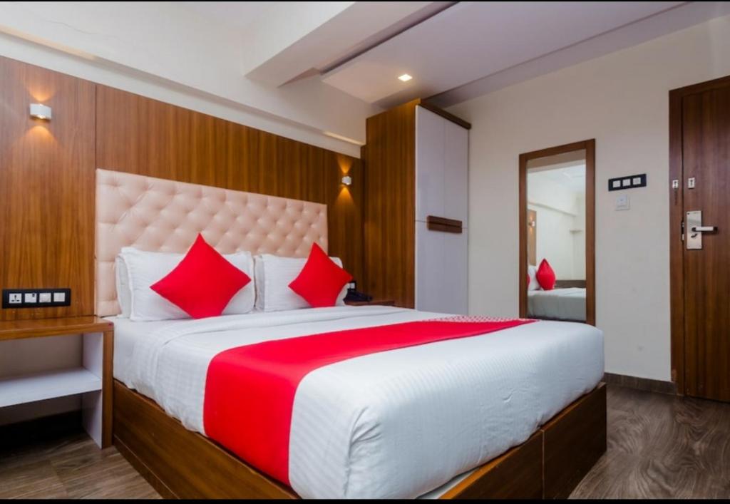 a bedroom with a large white bed with red pillows at Hotel Arma Residency in Mumbai