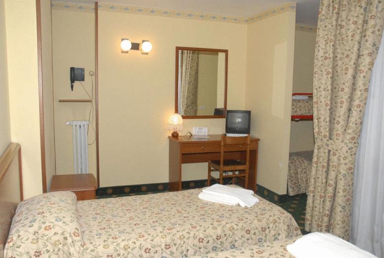 a bedroom with a bed and a desk with a computer at Hotel Biancaneve in Sestriere