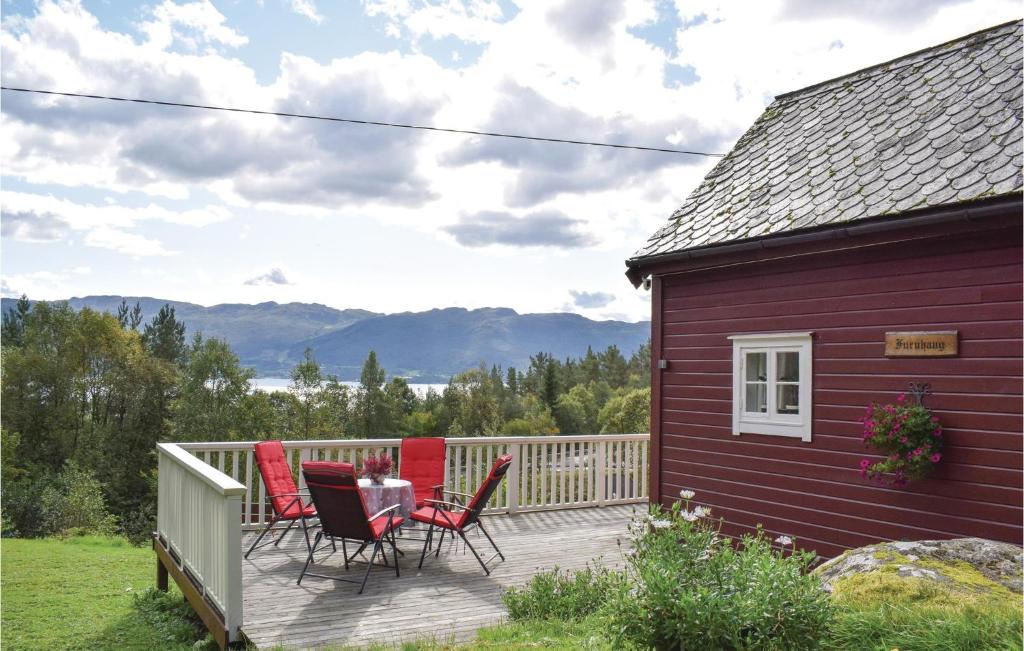 een rood huis met stoelen op een terras bij Lovely Home In Utker With House Sea View in Utåker