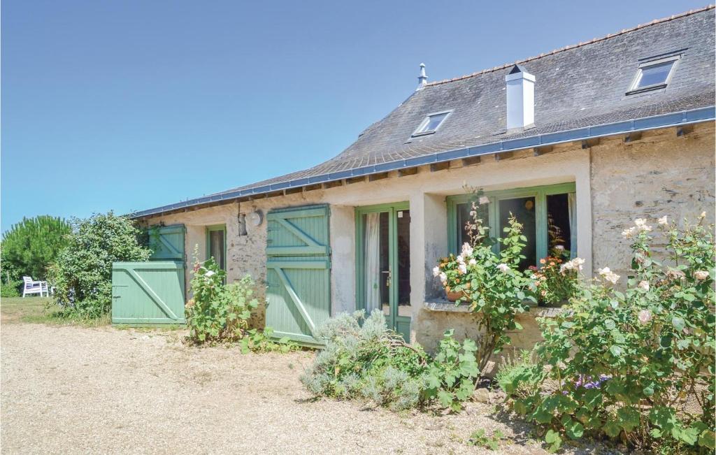 ein altes Steinhaus mit grünen Türen und Blumen in der Unterkunft Stunning Home In St Jean Des Mauvrets With Kitchen in Saint-Mélaine-sur-Aubance